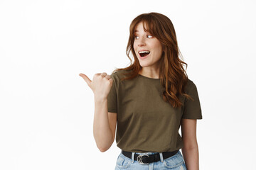 Amazed happy girl turn head, pointing left and looking at advertisement with excited smiling face,...