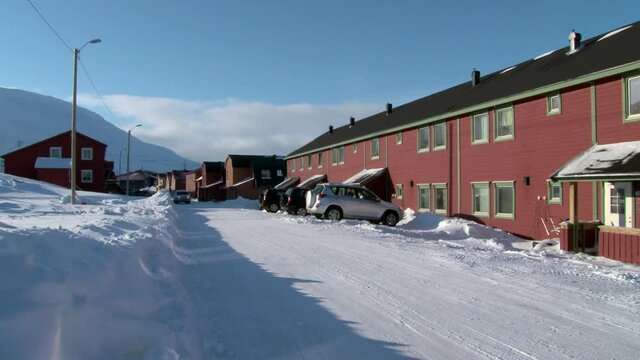 LONGYEARBYEN, SVALBARD - 23 APRIL, 2015: Landscape and buildings, roads in Small town Longyear among snow capped mountains of Norwegian archipelago of Svalbard in early spring in Norway.