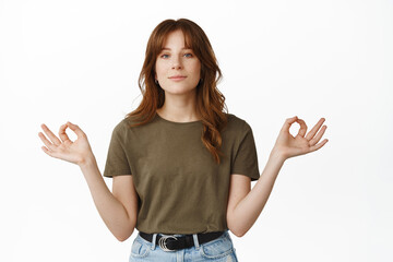 Calm and relaxed redhead girl meditating, holding hands sideways, nirvana zen pose, practice yoga, breathing and resting, standing over white background