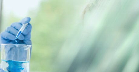 Composition of scientist holding beaker with blue liquid in laboratory and copy space