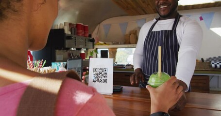 African american woman making payment from her smartphone by scanning the qr code at the food truck - Powered by Adobe