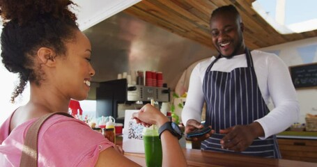 African american woman making payment from her smartwatch at the food truck - Powered by Adobe