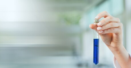 Composition of hand of lab technician holding test tube of blue liquid, with blurred copy space