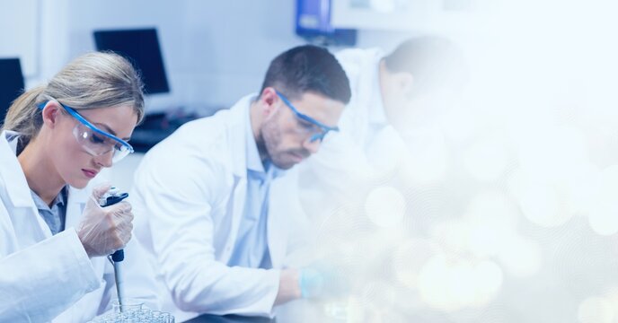 Composition of male and female lab technicians at work, with white bokeh copy space to right