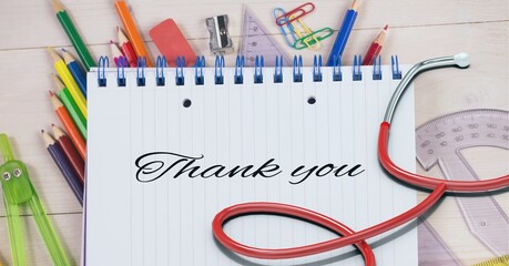 Composition of notebook with thank you note with pencils, rulers and stethoscope on wooden desk