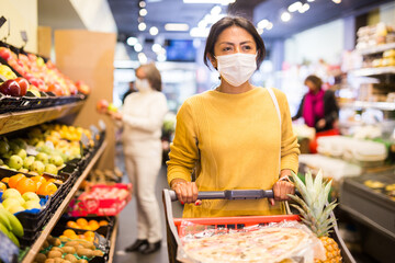 Woman in protective mask shopping at grocery store