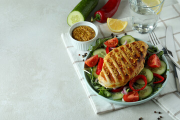 Salad with grilled chicken on white textured table
