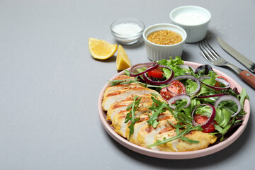 Concept of tasty eating with salad with grilled chicken on gray background