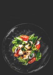 Salad with cucumber, tomato, red onion, pepper, parsley and Feta cheese on black background