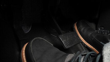 Foot pressing foot pedal of a car to drive. Accelerator and brake pedal in a car. Driver driving...