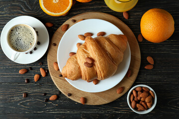 Concept of tasty breakfast with croissant on wooden background