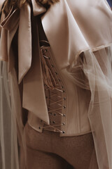 Part of a fashionable outfit - a beige corset with lacing. Back view