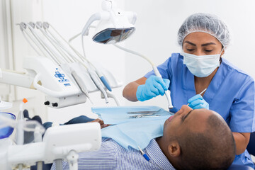 Dentist professional filling teeth for man patient sitting in medical chair