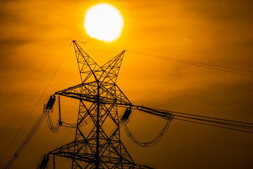 Silhouette effect of high voltage electric towers with electricity transmission power lines,...