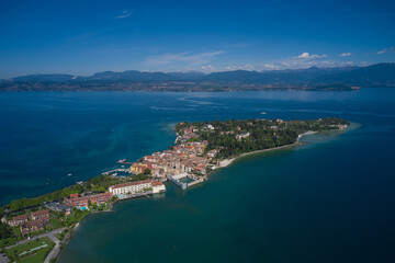 Naklejka na ściany i meble Aerial view of the island of Sirmione. Panorama of Lake Garda. Sirmione, Lake Garda, Italy. Peninsula on a mountain lake in the background of the alps. Castle on the water in Italy.