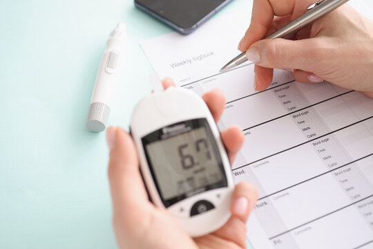Glucometer with blood test results in patient hand fills in results in daily report