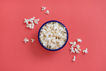Bowl of fresh popcorn with blue line, bowl on pink background