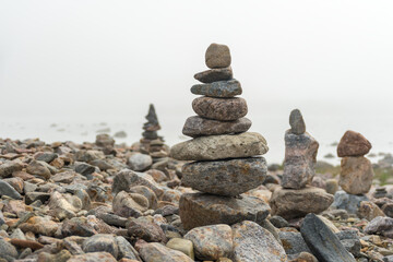 Stack or pile of stones cairn on foggy beach. Balance and harmony concept