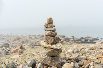 Stack or pile of stones cairn on foggy beach. Balance and harmony concept
