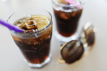 Two glasses with cola ice and lemon are on table
