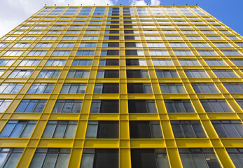 Beautiful yellow building and cloudy sky. Modern apartment building flat estate concept. Outdoor residential facility. Low angle shot of modern architecture