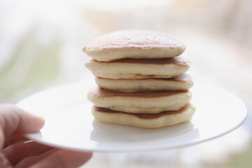 Stack of delicious pancakes lie on white plate