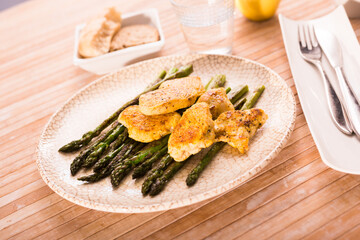 fried chicken breast pieces with asparagus on white plate