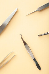 Beauty and fashion concept - tools for Eyelash Extension Procedure. Tweezers on beige background. Copyspace mockup