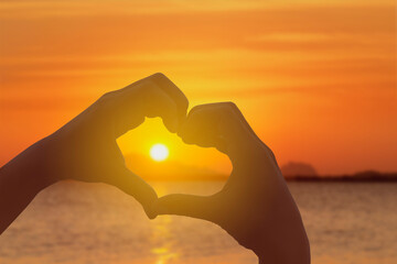 hand and heart shape at sea sunset summer nature background