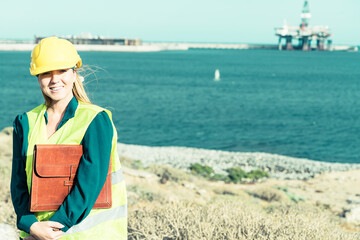 A portrait of an industrial woman engineer standing in an industrial port. Industry and professional job concept.