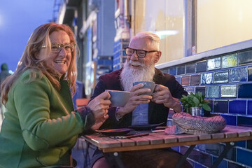 Senior couple having fun drinking at coffee bar on traveling. Mature man and woman wife on active elderly vacation. Happy retirement concept with retired people together.