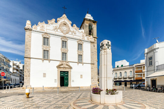 Square with white church and monument in Olhao, Portugal