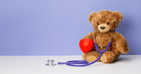 Teddy bear with a stethoscope and a heart on a purple background. Family doctor or pediatrician...