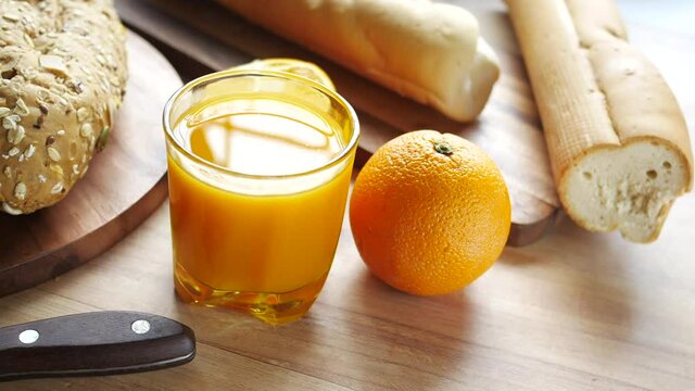 glass of orange juice and whole grain bread on table 