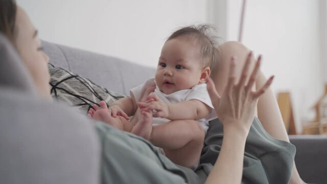 asian woman mother holding heavy baby infant get hurt in wrist and massaging to relieve pain. mother suffering from holding baby. tendon joint injury.
