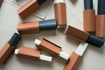 composition with construction paper objects in brown, triangular forms stuffed with curled black paper, and long rectangular boxes in beige on blank letter paper