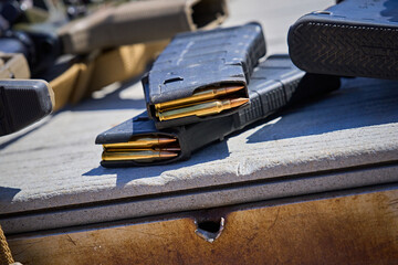 AR15 Rifle Magazines stacked on a table next to rifles at a shooting range