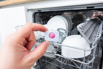 Dishwasher tablet in hand. Soap Dishwashing tablet