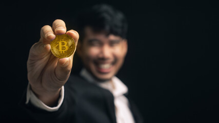 Selective focus cryptocurrency bitcoin coin on hand. Asian man successful holding in hand symbol of...