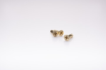 Three brass screws scattered on a white surface