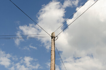 Electric pole with wires against the blue sky	