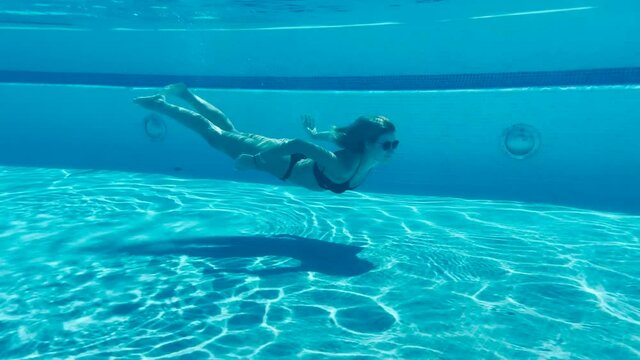 Beautiful young lady swimming underwater slow motion
