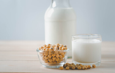 Soybean seeds in glass bowl And milk in  glass bottle  on wooden table.
