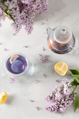 Decorative composition with a Bouquet of lilacs on a light kitchen interior. A cup of purple tea,...