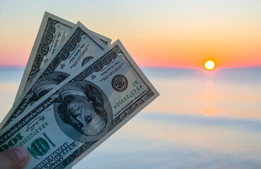 Three hundred dollar bills on background of sea surface at sunset dawn
