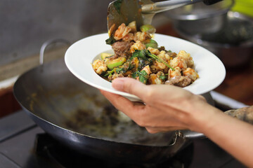 cooking stir fried food on plate in the kitchen scenery.