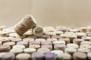 Closeup macro of corks with sign ENJOY and stamped withe on wine corks mosaic. Soft light, selective focus, shallow depth of field, blurred background. Space for copy. Wine advertising culture concept