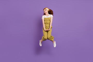 Full length body size view of attractive cheerful shy girl jumping having fun isolated over violet purple color background