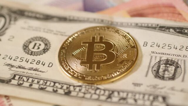 Bitcoin coin on top of 50 dollar bill. Close up.