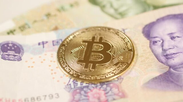 Bitcoin coin on top of Chinese yuan bill. Close up. 